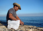 Pescador preparando la carnada en el muro del Malecón